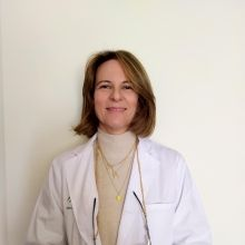 Person wearing a white coat with a plain background
